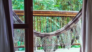 A hammock suspended between bamboo railings, with a view of lush greenery outside. - VELINN Pousada Bali Itamambuca (Ubatuba)