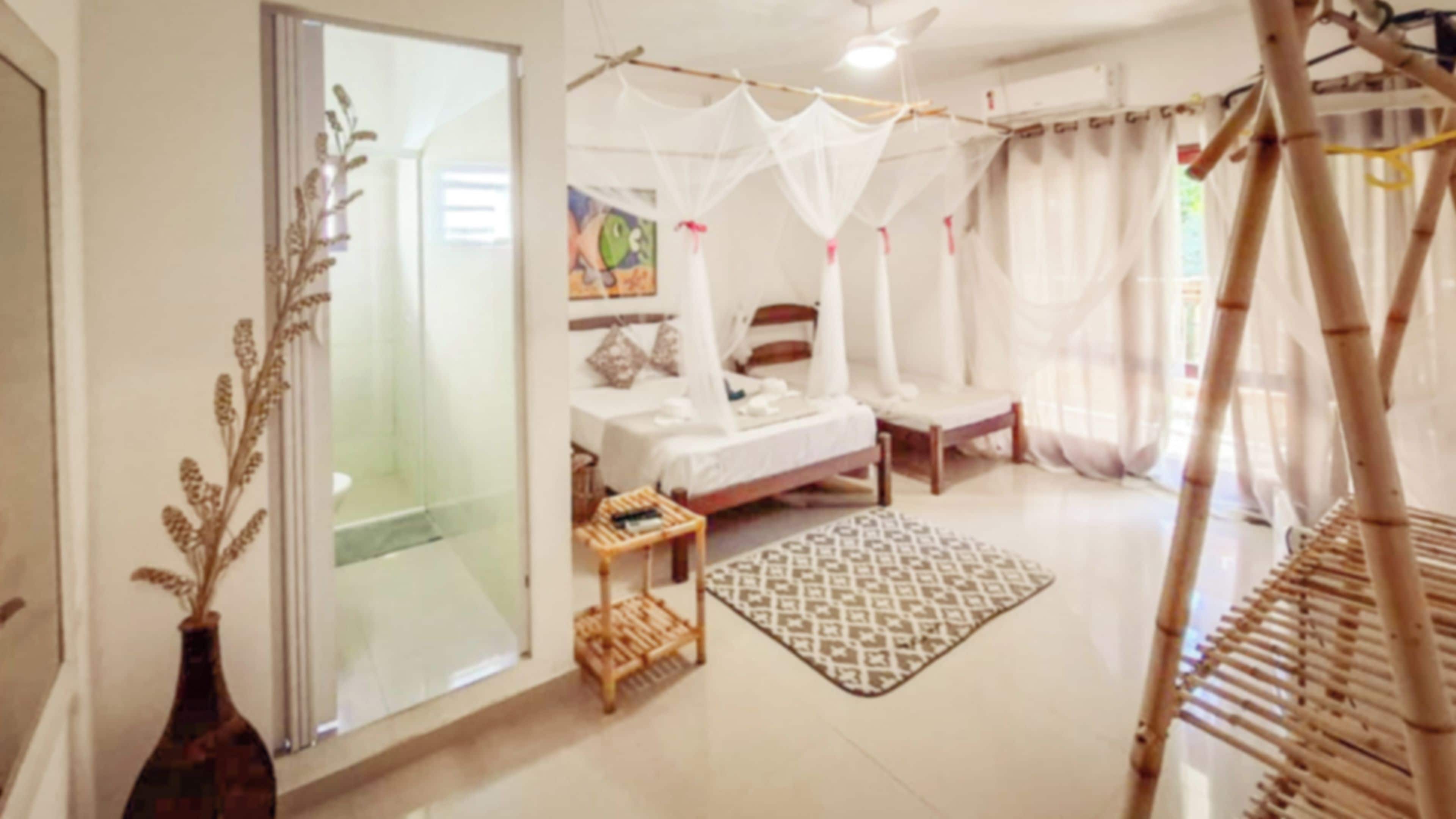 Un dormitorio con cama, mesita de noche y ventana con cortinas.