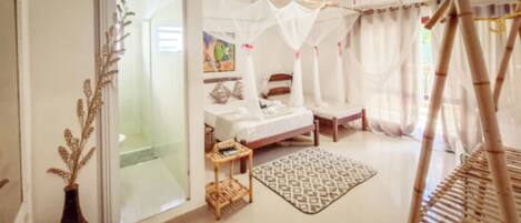 Un dormitorio con cama, mesita de noche y ventana con cortinas.