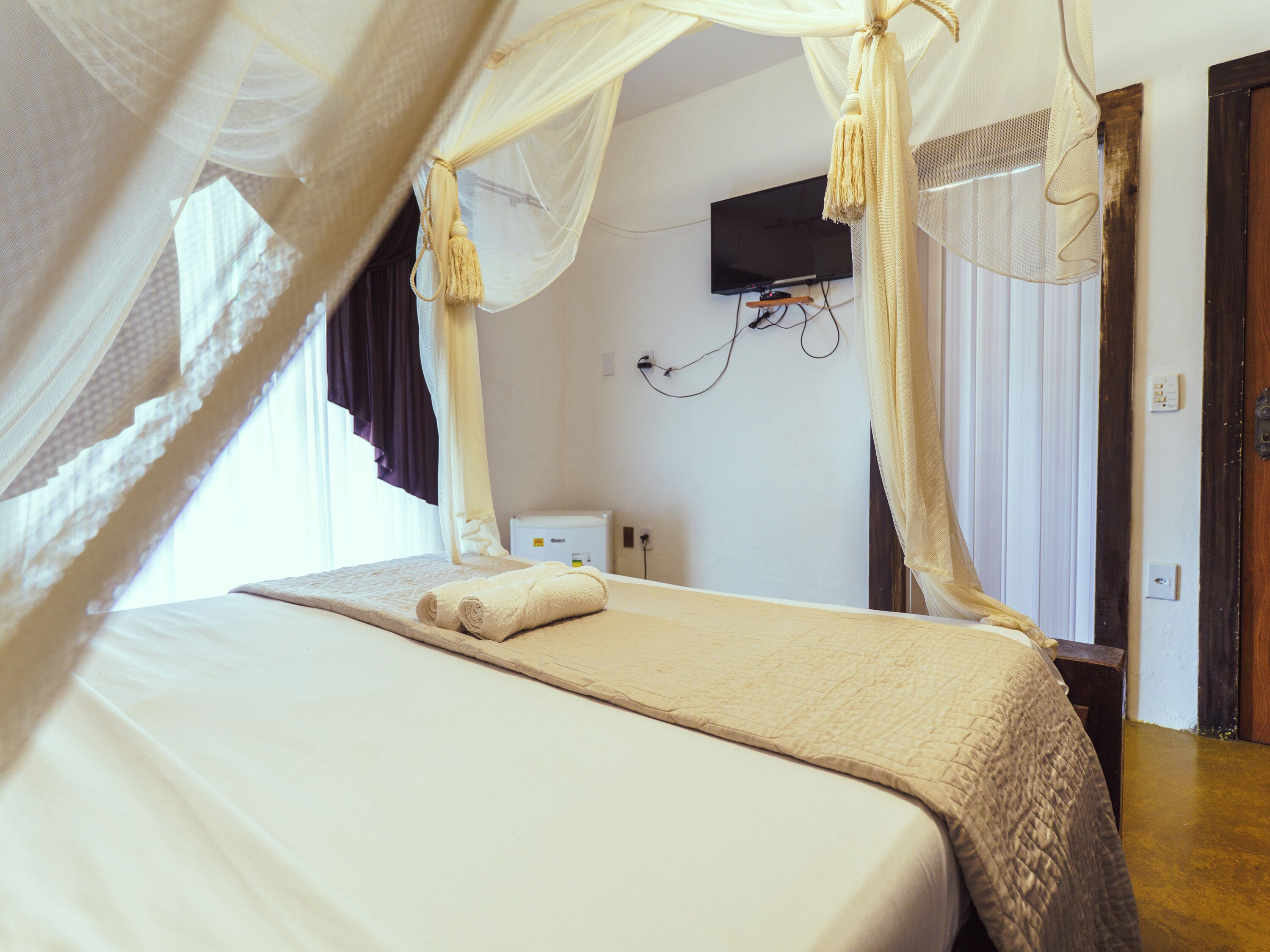A bedroom with a bed, a TV mounted on the wall, and a bedside table.