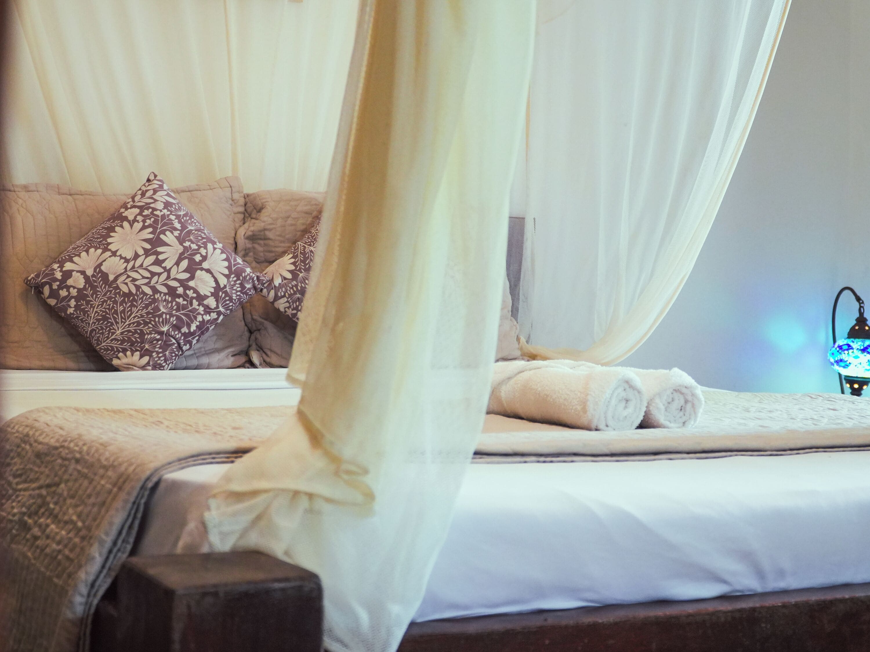 Ein Bett mit Baldachin, Kissen und einer Lampe.
