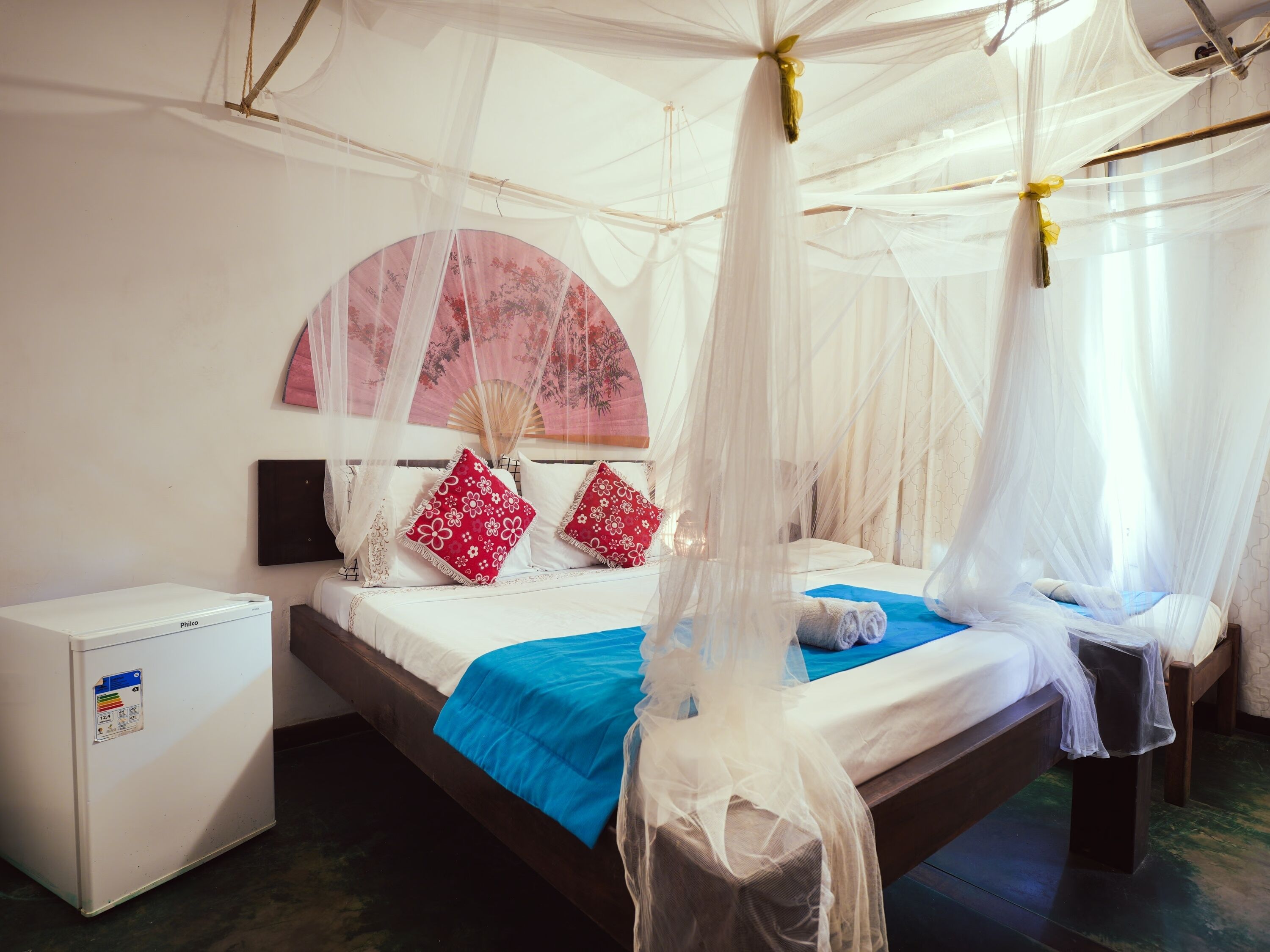 Un dormitorio con cama bajo dosel, una mesita de noche pequeña y un calentador fijado a la pared.