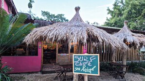 A SURF CAFE with a thatched roof, wooden tables, and a chalkboard sign. - VELINN Pousada Bali Itamambuca (Ubatuba)