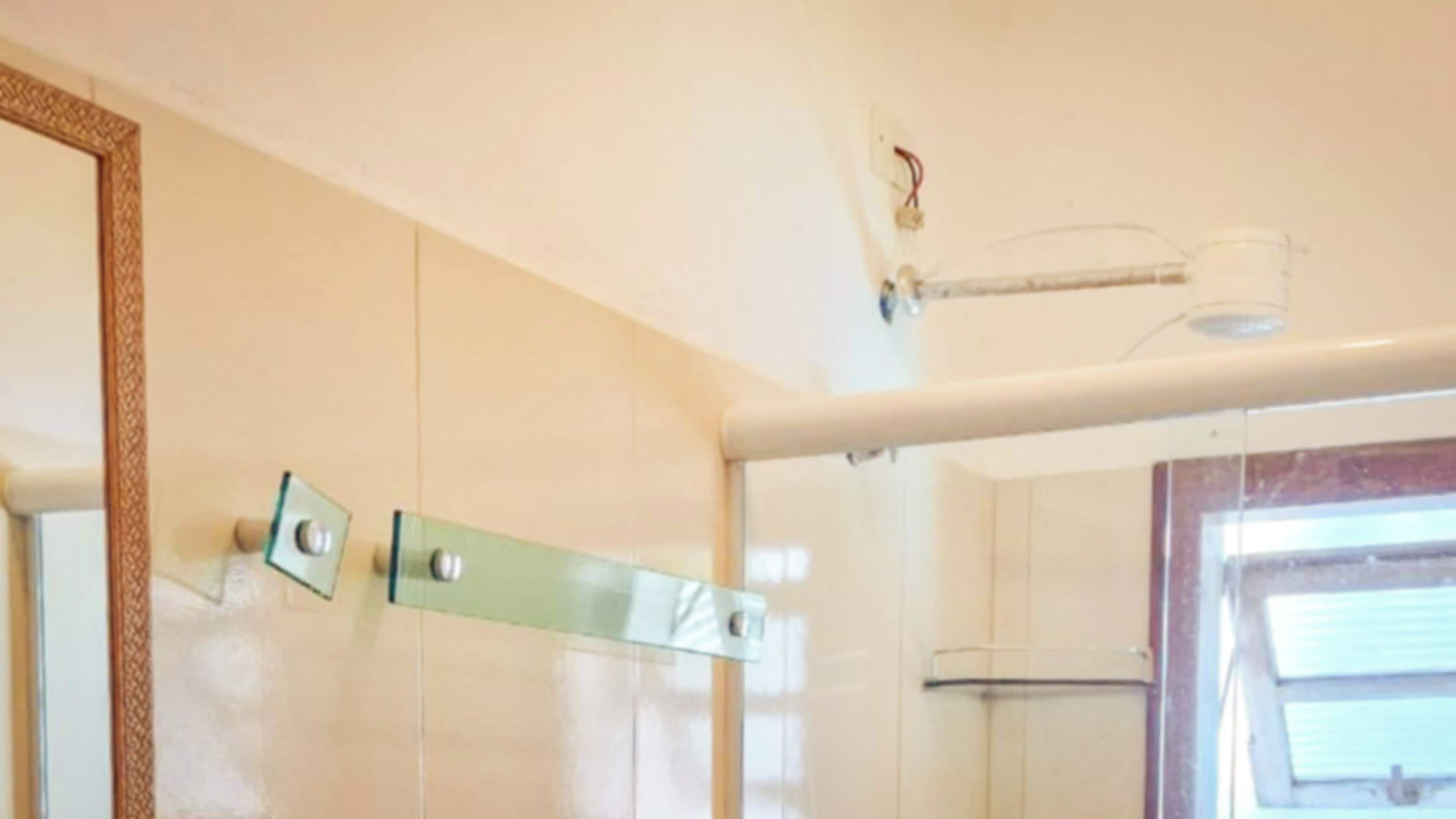 A bathroom with a glass shower enclosure, a towel rack, and a mirror on the wall.
