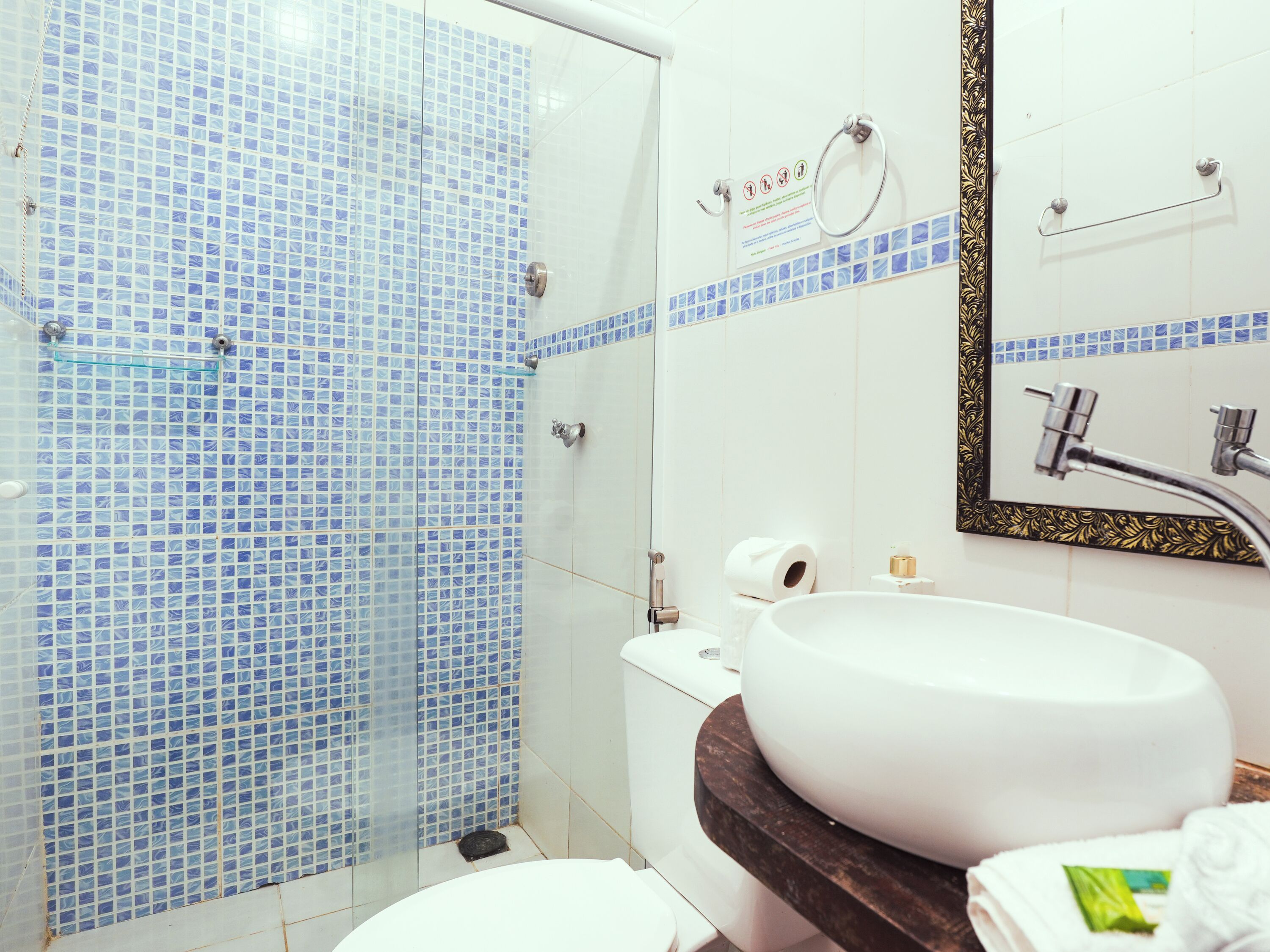 A bathroom with a shower, toilet, sink, and a mirror with a decorative frame.