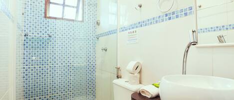 A bathroom with a glass shower enclosure, a toilet, a sink, and a mirror.