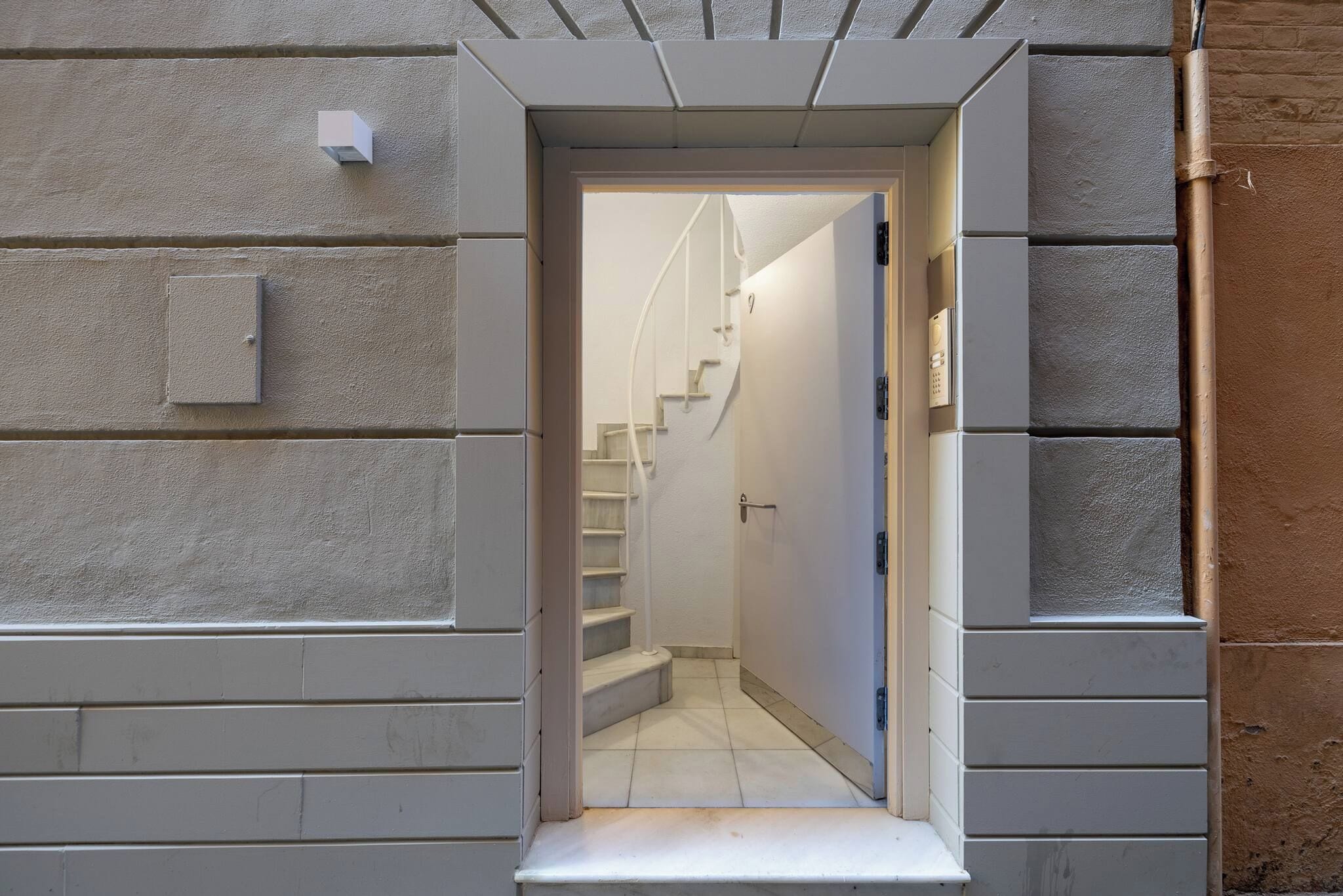 Un pasillo estrecho que conduce a una escalera, con una puerta al final.