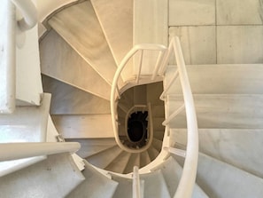 A spiral staircase with white railings and a central void.