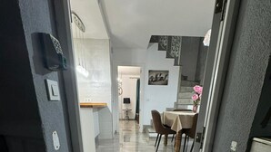 Un interior moderno con comedor, escalera y cocina a la vista.