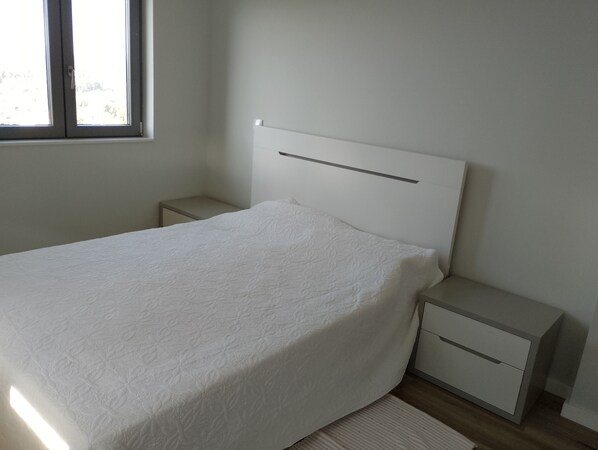 A bedroom with a bed, nightstands, and a window.
