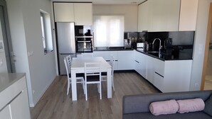 A modern kitchen with white cabinets, a dining table with chairs, and a grey sofa with a pink cushion. - Accommodation in house with shared pool, 10mn from Braga. Weekly rental (BRAGA)