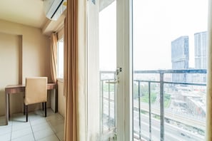 A room with a desk, chair, and a view of a cityscape through a large window.