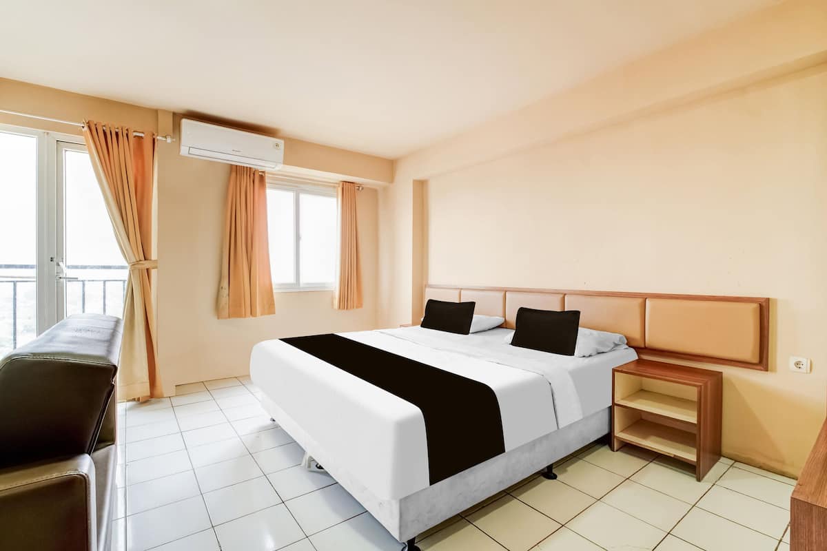 Une chambre d’hôtel avec un lit, une table de chevet, une chaise et une fenêtre avec des rideaux.
