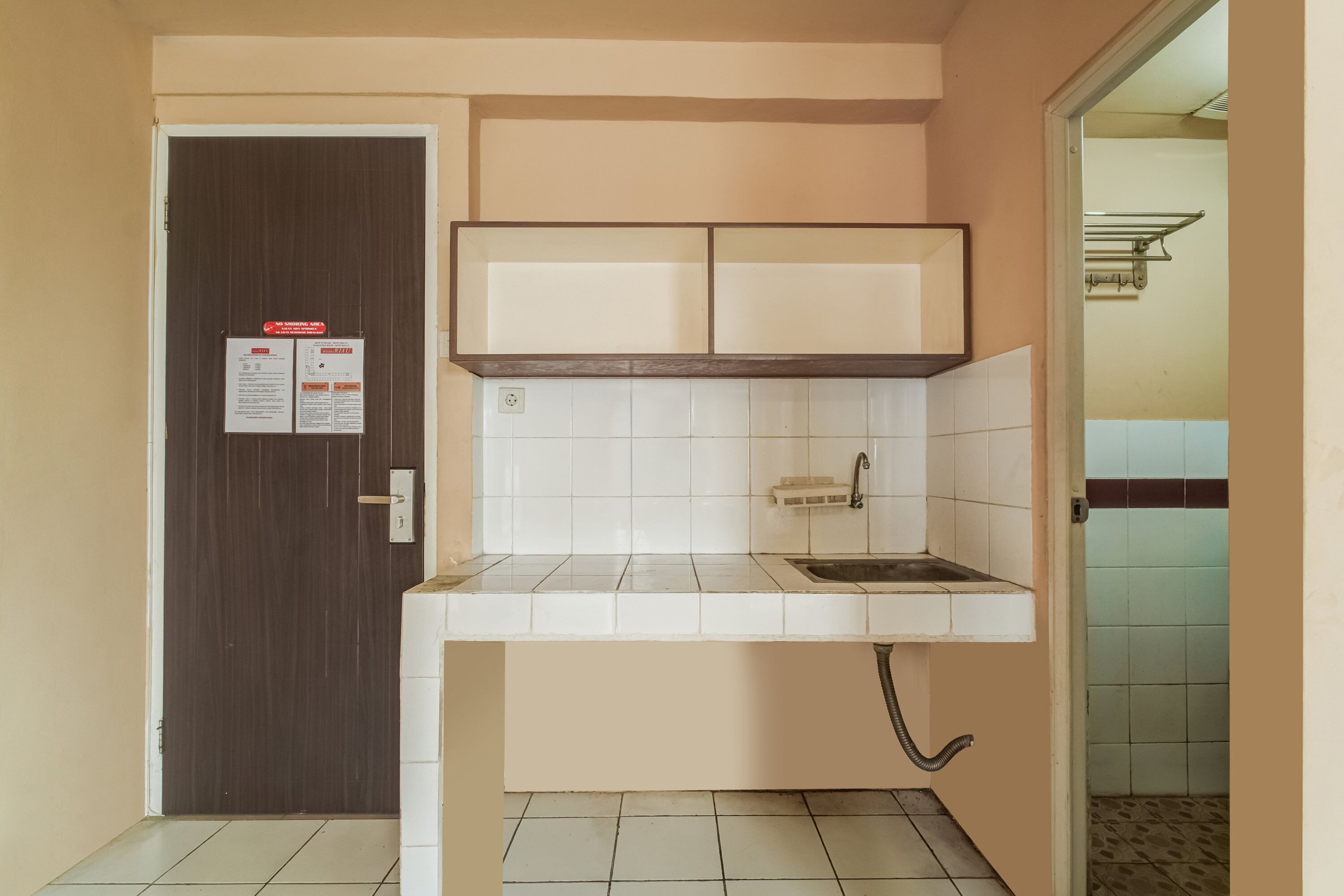 Uma cozinha compacta com azulejos brancos, uma pia e um armário acima.
