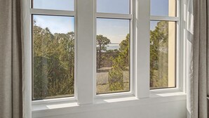 A window with three panes, offering a view of trees and a distant landscape. - Elation 2BR: Sunset Views & Steps to Baytowne (Miramar Beach)