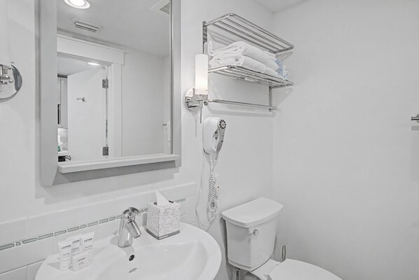A bathroom with a white sink, mirror, towel rack, and toilet.