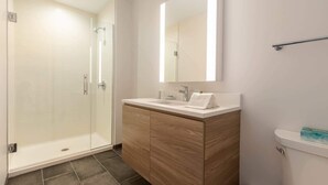 A modern bathroom with a glass shower enclosure, a wooden vanity, and a large mirror. - Seaport Apt with City Views and Pool (Boston)