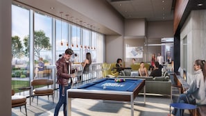A modern indoor pool area with a pool table, seating, and large windows.