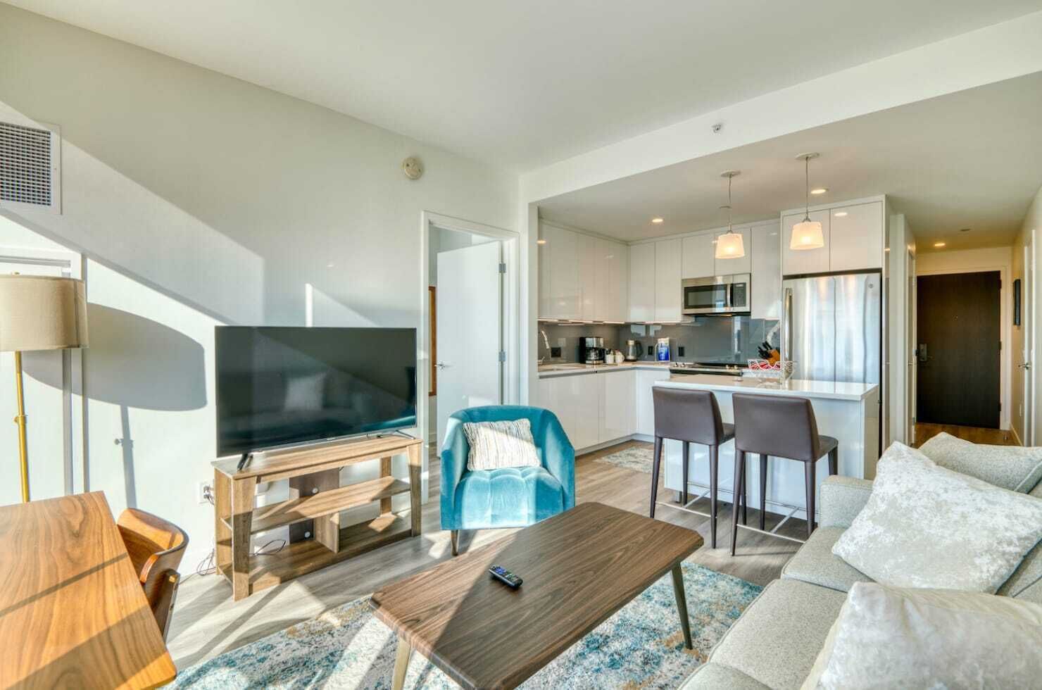 Een moderne woonkamer met een flatscreen televisie, een blauwe fauteuil, een houten salontafel en een bank.