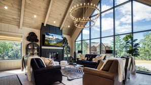 A spacious living room with a large fireplace, comfortable seating, and a view of the outdoors. - WALDEN'S RIDGE SPLASH! LUXURY 2 BEDROOMS! (Sevierville)