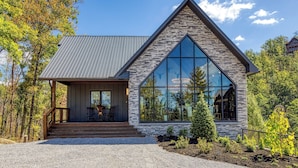 A modern house with a stone facade, large windows, and a wooden porch. - WALDEN'S RIDGE SPLASH! LUXURY 2 BEDROOMS! (Sevierville)