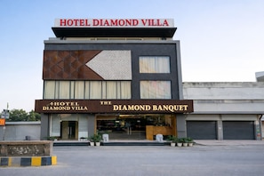A modern building with a sign reading "HOTEL DIAMOND VILLA" and "THE DIAMOND BANQUET" on the ground floor.