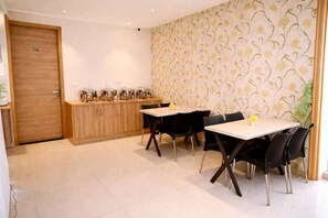 A dining area with a table and chairs, a wooden counter with pots, and a patterned wall.