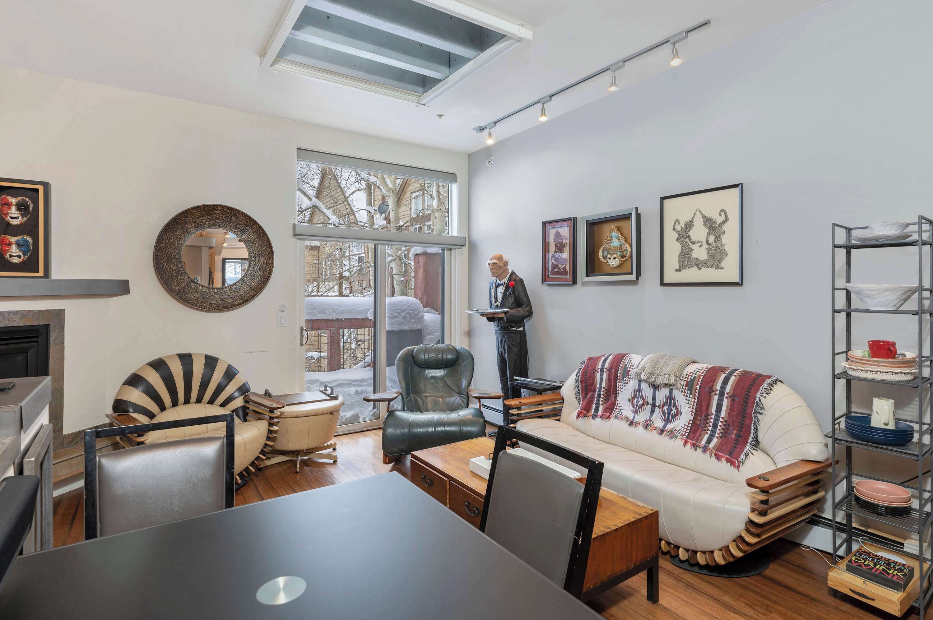 A modern living room with a sofa, chairs, a dining table, and a fireplace.