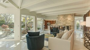 A spacious living area with a stone fireplace, modern furniture, and large windows offering a view of the outdoors. - 3954 Lilli Pad - Remodeled, Private Primary Suite (Carmel)