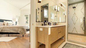 A modern bathroom with a wooden vanity, large mirrors, and a shower with a glass door. - 3954 Lilli Pad - Remodeled, Private Primary Suite (Carmel)