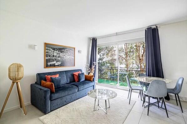 A modern living room with a sofa, a coffee table, and a dining area with chairs and a table.