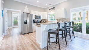 A modern kitchen with a central island, stainless steel appliances, and a view of the outdoors. - Beautiful Home & Carriage House with Golf Cart (Destin)