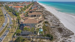 A coastal residential area with a large house featuring a swimming pool, a beach, and a road with vehicles. - Beautiful Home & Carriage House with Golf Cart (Destin)
