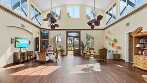 A spacious lobby with high ceilings, large windows, and a central open door leading outside. - Beautiful Home & Carriage House with Golf Cart (Destin)