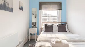 Ein Schlafzimmer mit Bett, Nachttisch, Spiegel und Fenster mit Jalousien.