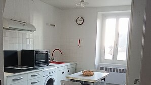 A modern kitchen with white appliances, a dining table, and chairs.