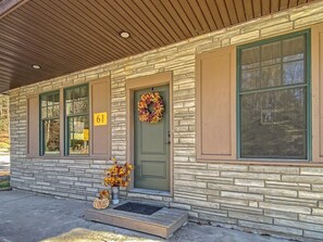 A building with a stone facade, a green door, and a number '61' sign. - Ronnie's Guest House (Inlet)