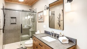 Une salle de bain moderne avec une douche à parois de verre, un meuble-lavabo en bois et un grand miroir.
