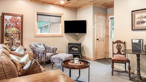 Un salon chaleureux avec une cheminée, un téléviseur et des fauteuils confortables.