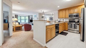 A modern kitchen with wooden cabinets, stainless steel appliances, and a central island. - Mountain Escape 3 BR Condo at Okemo w/ Fireplace (Ludlow)