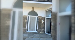 A building entrance with a door, a small covered area, and a stone wall. - Modern new redeveloped studio Apartment in Clacton (Essex)