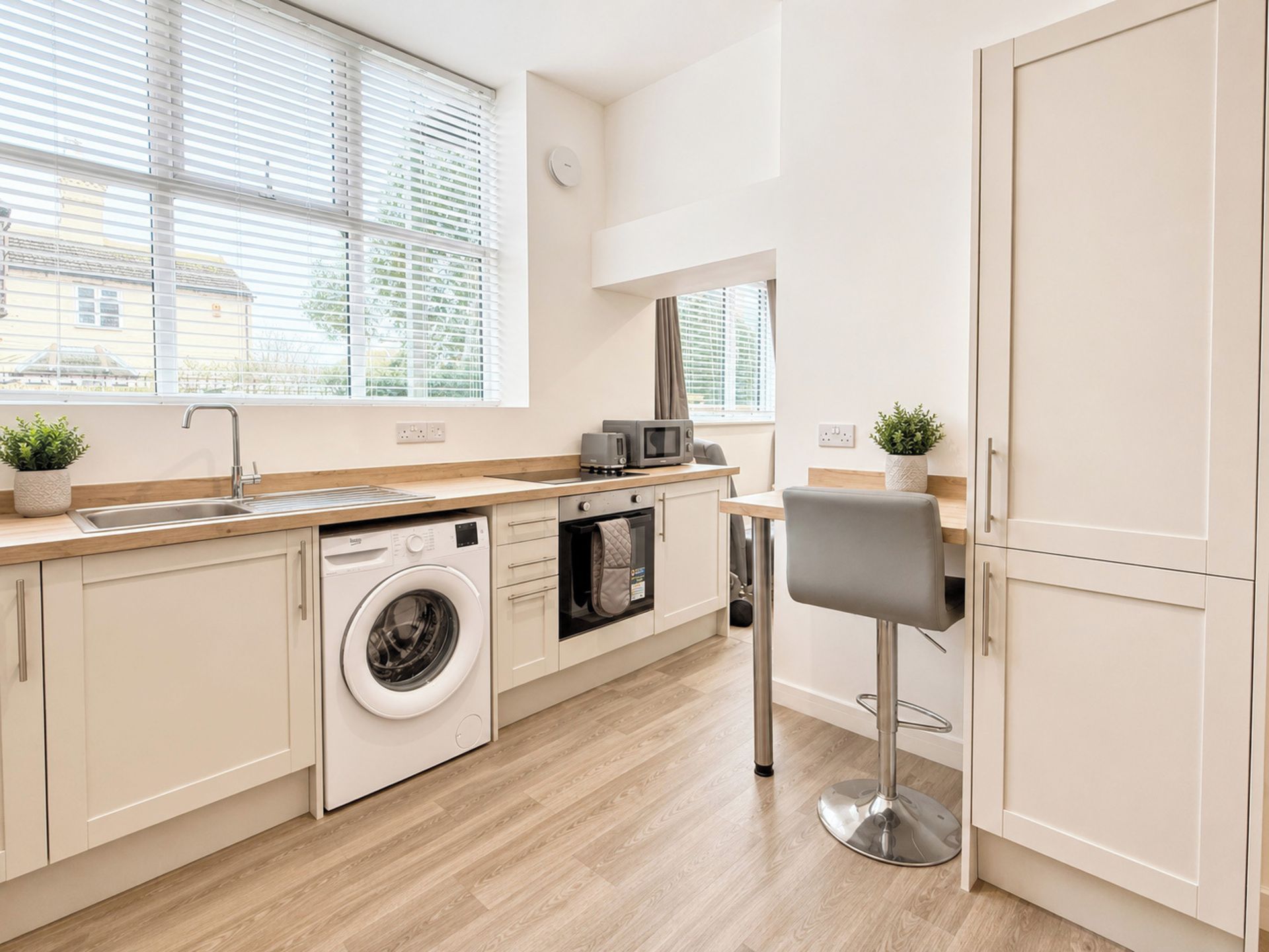 A modern kitchen with a washing machine, oven, and microwave.