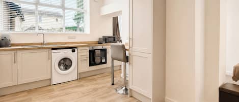 A compact kitchen with a washing machine, microwave, and a sink.