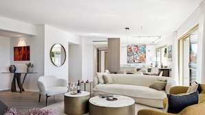 Un salon moderne avec un canapé, deux petites tables rondes et un fauteuil.