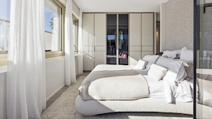 Une chambre moderne dotée d’un grand lit, d’un dressing et offrant une vue sur l’extérieur.
