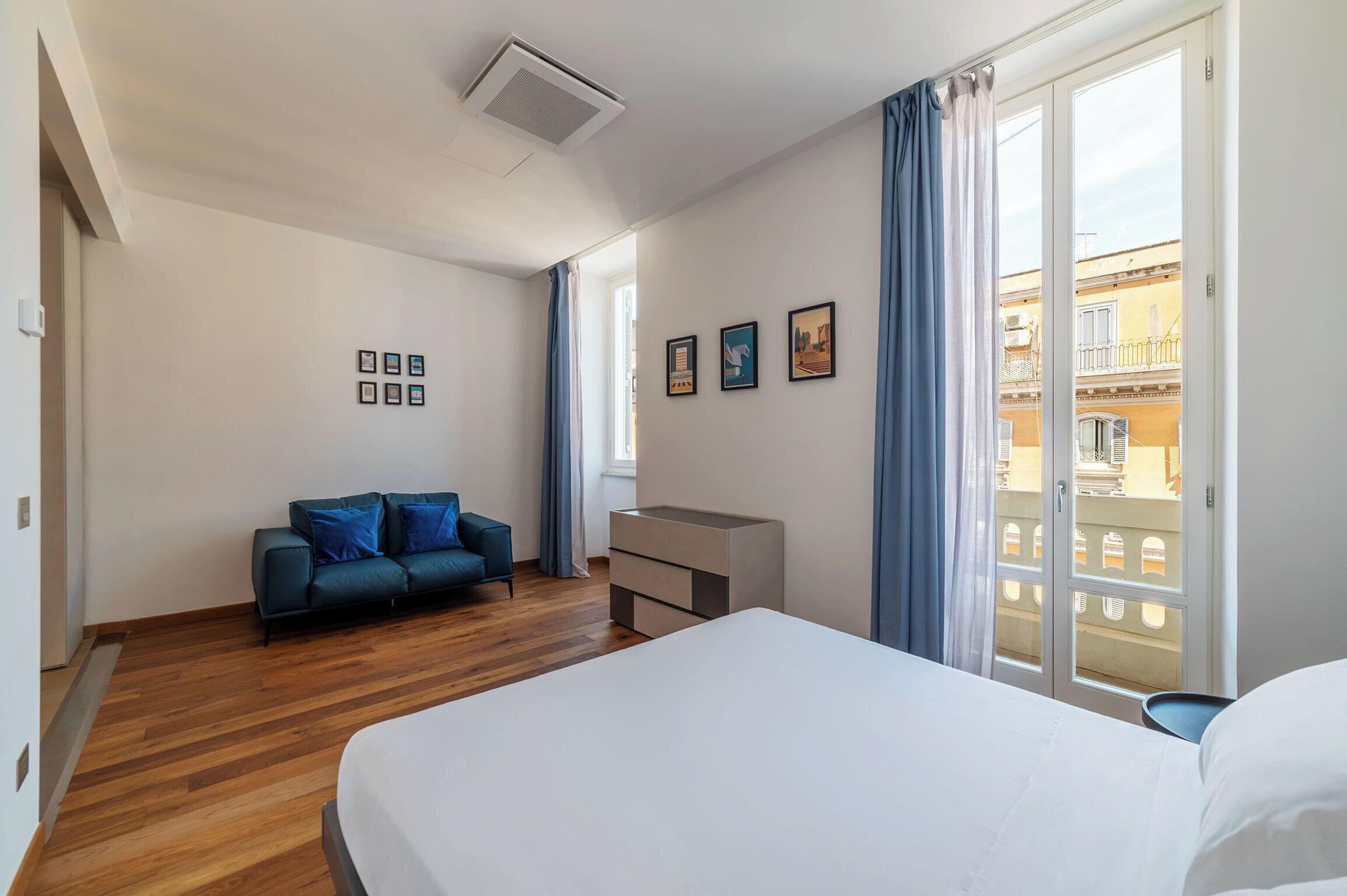 Una habitación de hotel con cama, sofá, escritorio y balcón con vistas.
