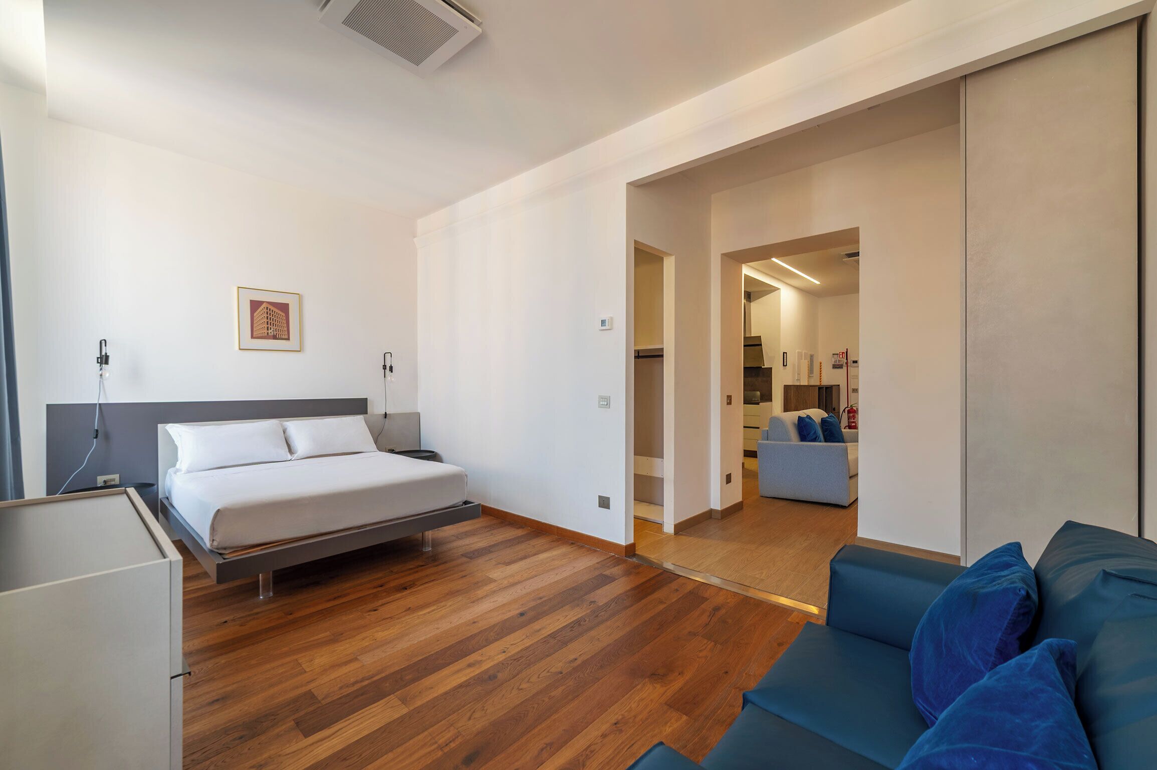 A modern hotel room with a bed, a sofa, and a desk.