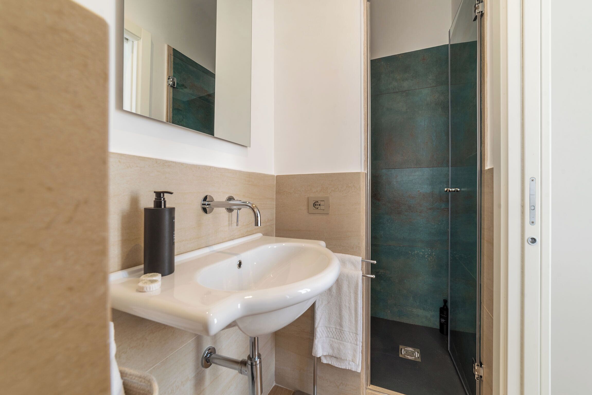 A bathroom with a white sink, a mirror, and a glass shower door.