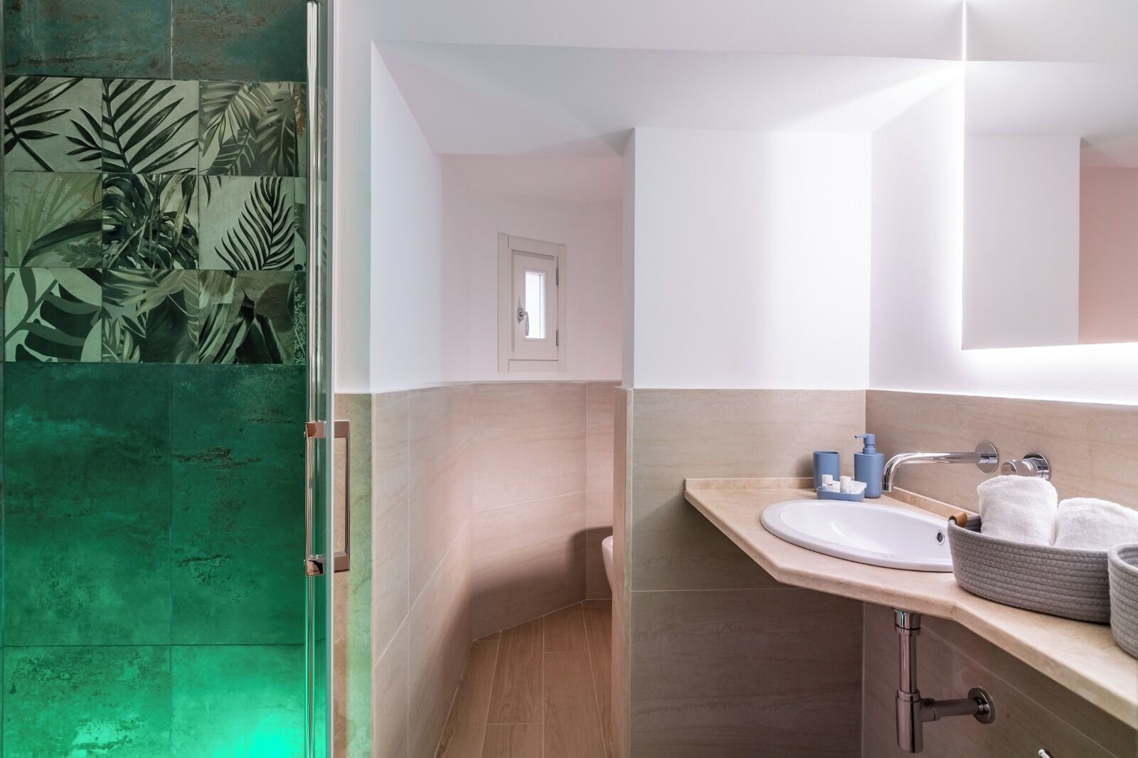 Un baño moderno con cabina de ducha de vidrio, un lavamanos con encimera color beige y un espejo sobre el lavamanos.