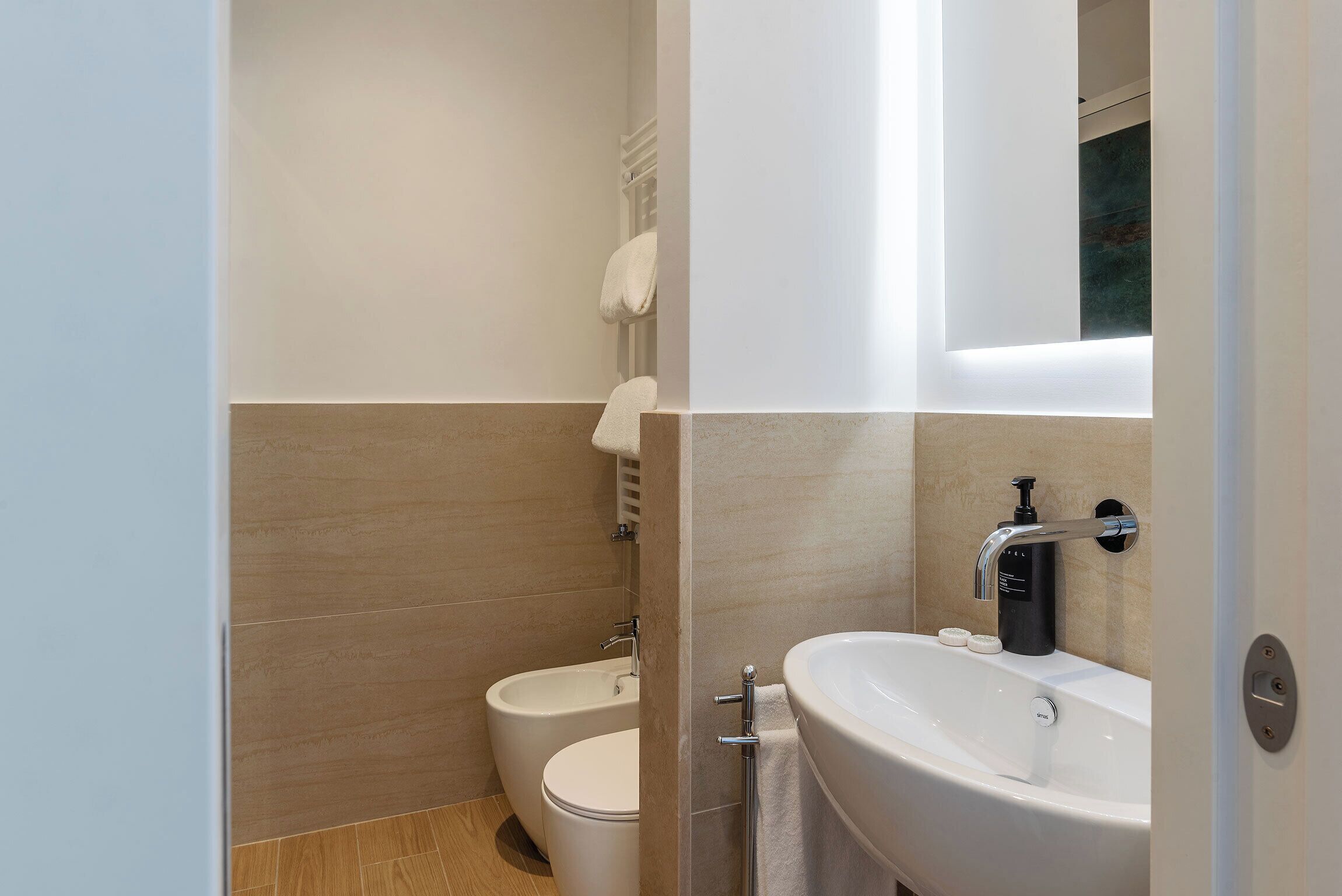 A modern bathroom with a bidet, toilet, and a large sink with a mirror.